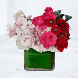 Pink and red flower arrangement in a green glass vase