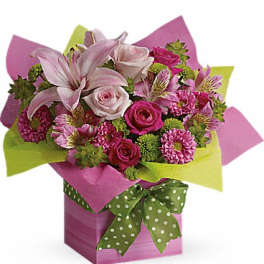 Bright pink and green mixed flower arrangement in a pink gift box with a green polka-dot bow
