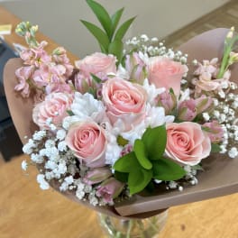 Bouquet of pink roses, white daisies, and baby's breath in brown paper