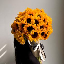 Large bouquet of sunflowers wrapped in burlap with a ribbon