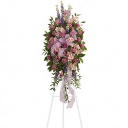 Standing floral spray of pink roses and purple flowers on an easel