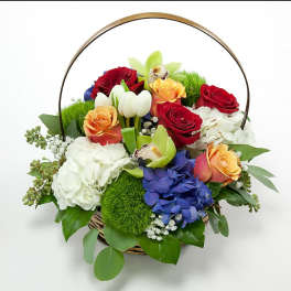 Basket of mixed roses, hydrangeas, and orchids with a metal handle