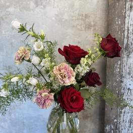 Bouquet of red roses and pink carnations in a clear glass vase