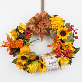 Fall wreath with sunflowers, orange flowers, a plaid bow, and a "Grateful & Blessed" pillow