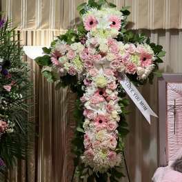 Large cross-shaped floral tribute with pink and white flowers on an easel