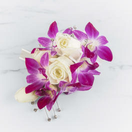 White roses with bright pink orchids and crystal accents in a small bouquet