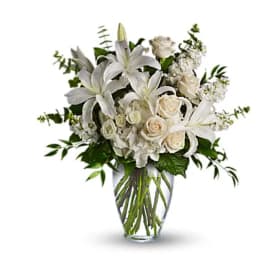 White lilies and roses arranged in a clear glass vase