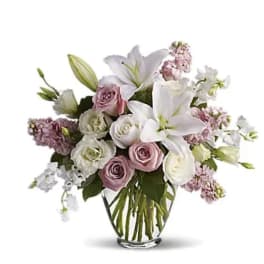 Bouquet of white lilies and pale pink roses in a clear glass vase
