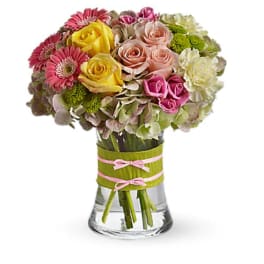 Mixed bouquet of roses, gerbera daisies, and hydrangeas in a glass vase