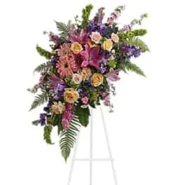 Standing floral spray with pink, purple, and yellow flowers on an easel