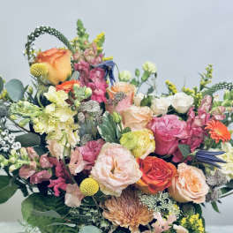 Mixed bouquet of roses, snapdragons, and chrysanthemums in a white vase
