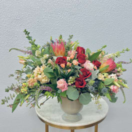 Mixed bouquet of red and pink roses with tropical blooms in a vase