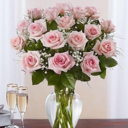 Pink roses arranged in a clear glass vase with baby's breath