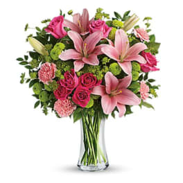 Pink lilies and roses arranged in a clear glass vase