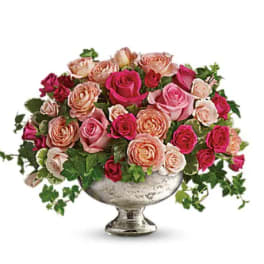 Pink and peach roses arranged in a silver pedestal vase