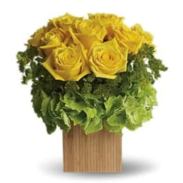 Yellow roses arranged above a green hydrangea cluster in a wooden box