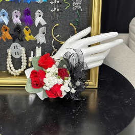 Red roses with white filler flowers and black ribbon on a mannequin hand