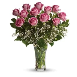 Pink roses arranged in a clear glass vase with white filler flowers
