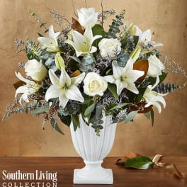 White lilies and roses arranged in a white pedestal vase