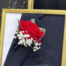 Red rose boutonniere with white baby's breath in a gold frame