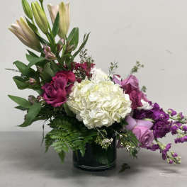 Bouquet of lilies, roses, and hydrangea in a dark vase