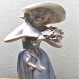 Ceramic figurine of a girl holding a small bouquet of flowers