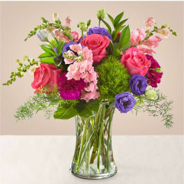 Mixed pink, purple, and white flowers in a clear glass vase