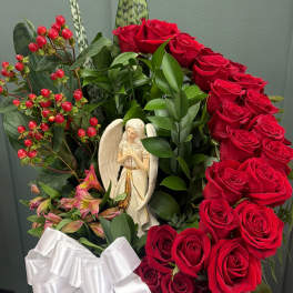 Red roses arranged in a white basket with a ribbon and angel figurine