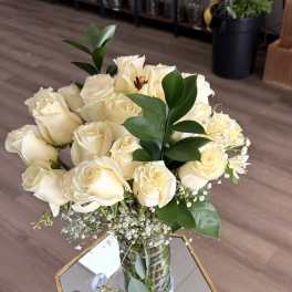 Bouquet of white roses in a clear glass vase with greenery