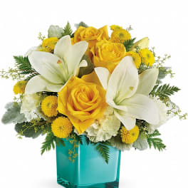 Yellow roses and white lilies in a turquoise glass vase