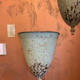 Rustic metal wall planter mounted on an orange wall