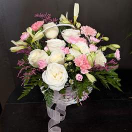 White and pink floral basket arrangement with a ribbon handle