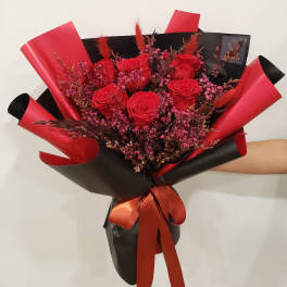 Bouquet of red roses wrapped in black and red paper with a ribbon