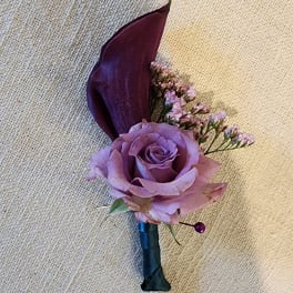 Purple rose boutonniere with a dark calla lily and small filler flowers