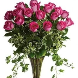 Bouquet of pink roses in a clear glass vase with trailing ivy
