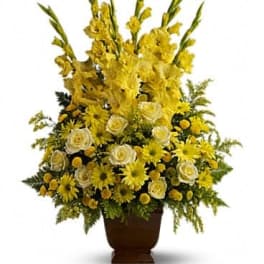 Tall yellow floral arrangement in a brown urn vase