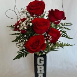 Red roses arranged in a tall black vase with a GRAD sign