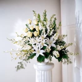 White lilies and cream roses arranged in a tall white vase