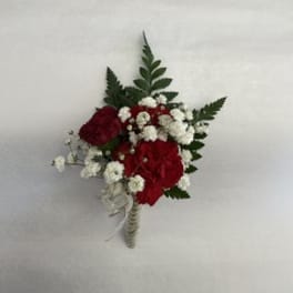 Red and white boutonniere with fern leaves and ribbon wrap