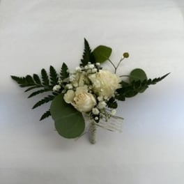 White floral boutonniere with greenery on a white background