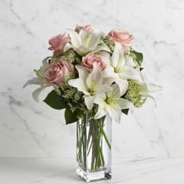 Pink roses and white lilies arranged in a clear glass vase