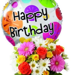 Birthday balloon above a colorful bouquet in a glass vase