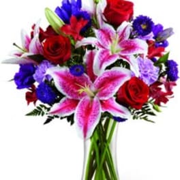 Bouquet of red roses and pink lilies in a clear glass vase