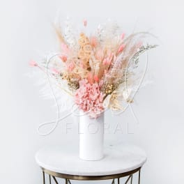 Pink dried floral arrangement in a white vase