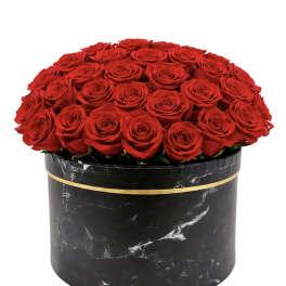 Round box of red roses in a black marble-pattern container