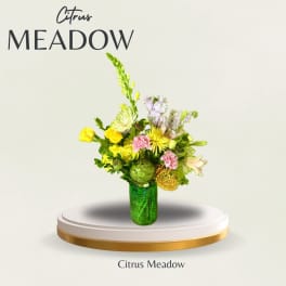 Mixed yellow and pink floral arrangement in a green glass vase