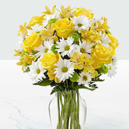 Yellow roses and white daisies arranged in a clear glass vase