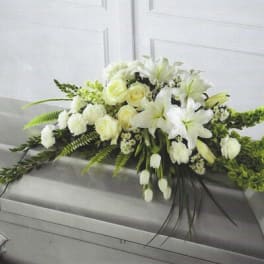 White floral casket spray with lilies and roses