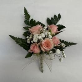 Small pink rose corsage with white baby's breath and dark greenery