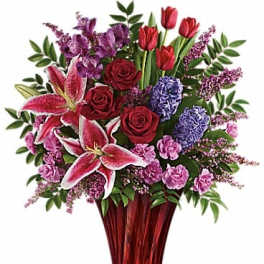 Bouquet of red roses, pink lilies, and purple flowers in a red vase